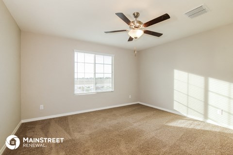 the spacious living room has carpet and a ceiling fan