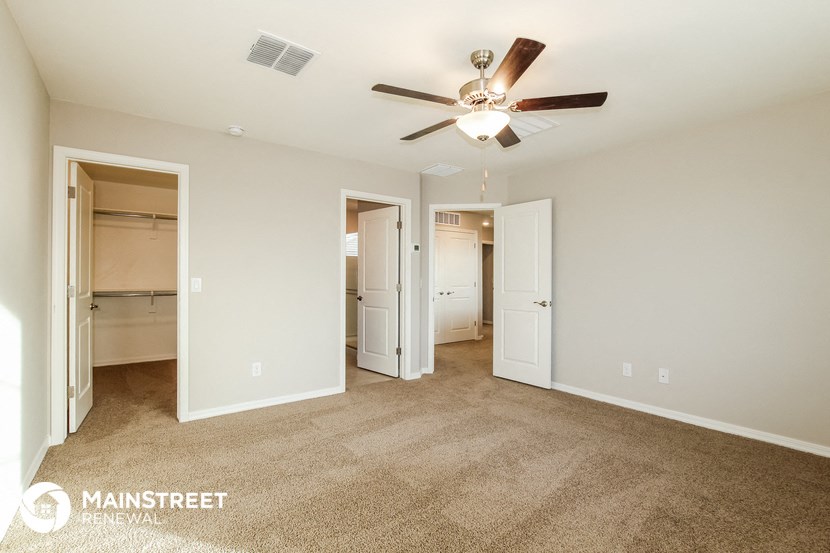 a spacious living room with carpet and a ceiling fan