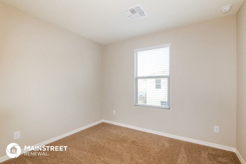 the spacious bedroom with carpeted flooring and a window