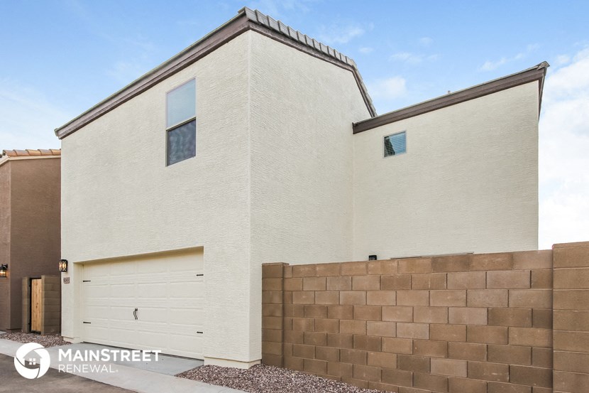a large white house with a garage and a brick wall