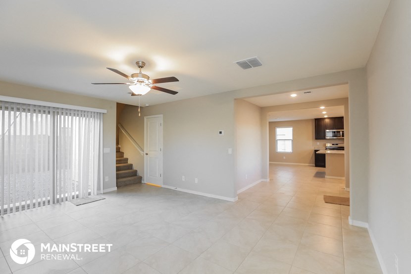 an empty living room with a ceiling fan and a staircase