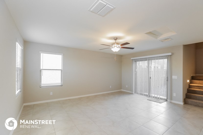 an empty living room with a ceiling fan and a staircase