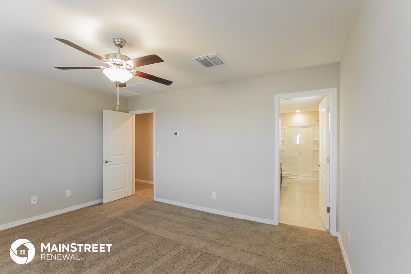 a living room with a ceiling fan and a door to a bathroom