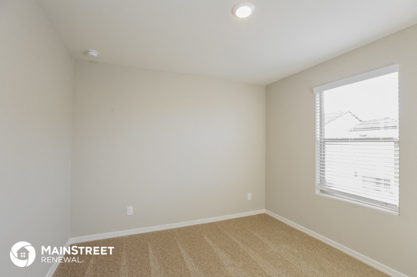the upstairs bedroom has a large window and carpeted flooring