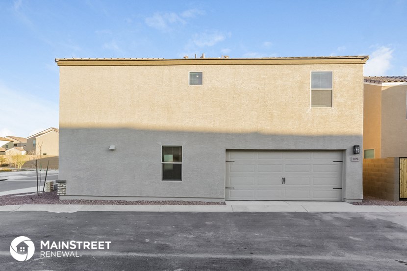 the front of a tan building with a garage door