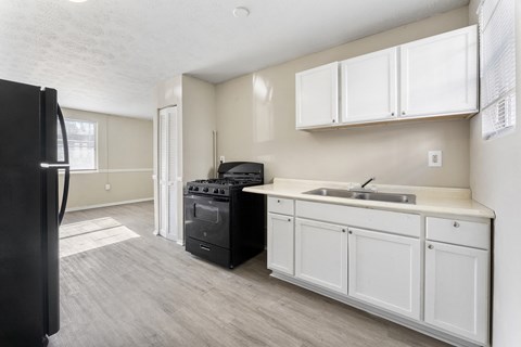 an empty kitchen with white cabinets and a black stove