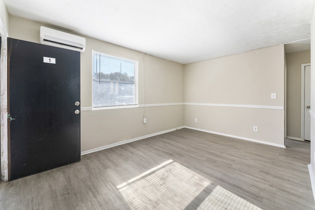 an empty living room with a black door and a window