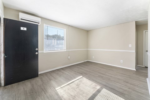 an empty living room with a black door and a window