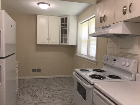 A kitchen with a white stove and a white fridge.