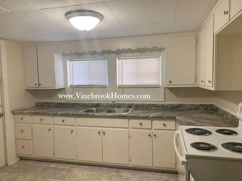 A kitchen with white cabinets and a granite countertop.