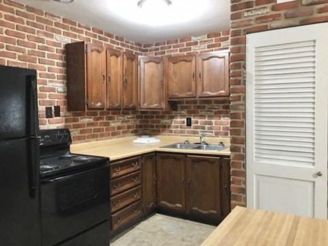 A kitchen with a black stove and wooden cabinets.