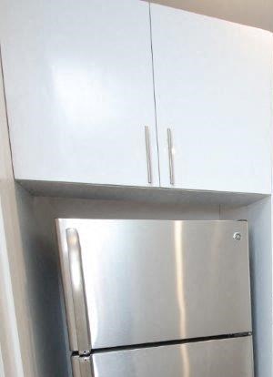 a kitchen with white cabinets and a stainless steel refrigerator