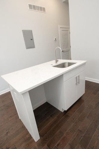 an empty kitchen with a sink and a white counter top