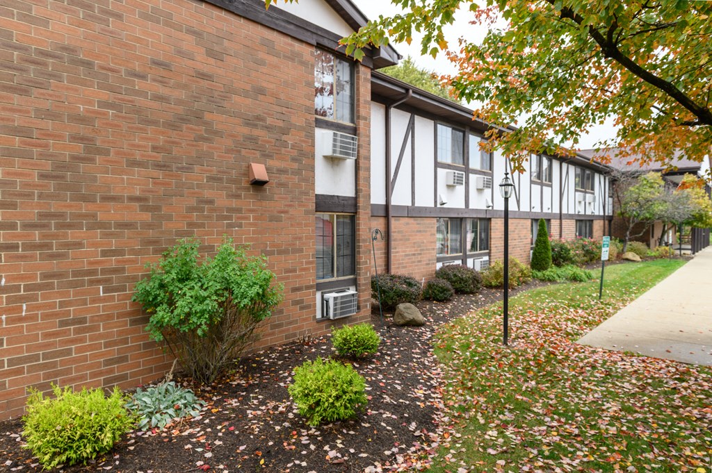 exterior view of a brick apartment building with a sidewalk and landscaping
