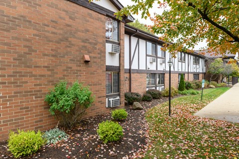 exterior view of a brick apartment building with a sidewalk and landscaping
