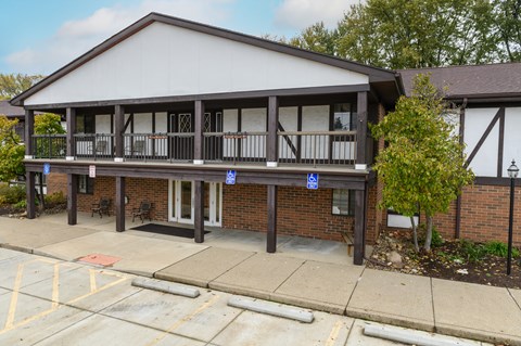 the front of a building with a porch and a parking lot