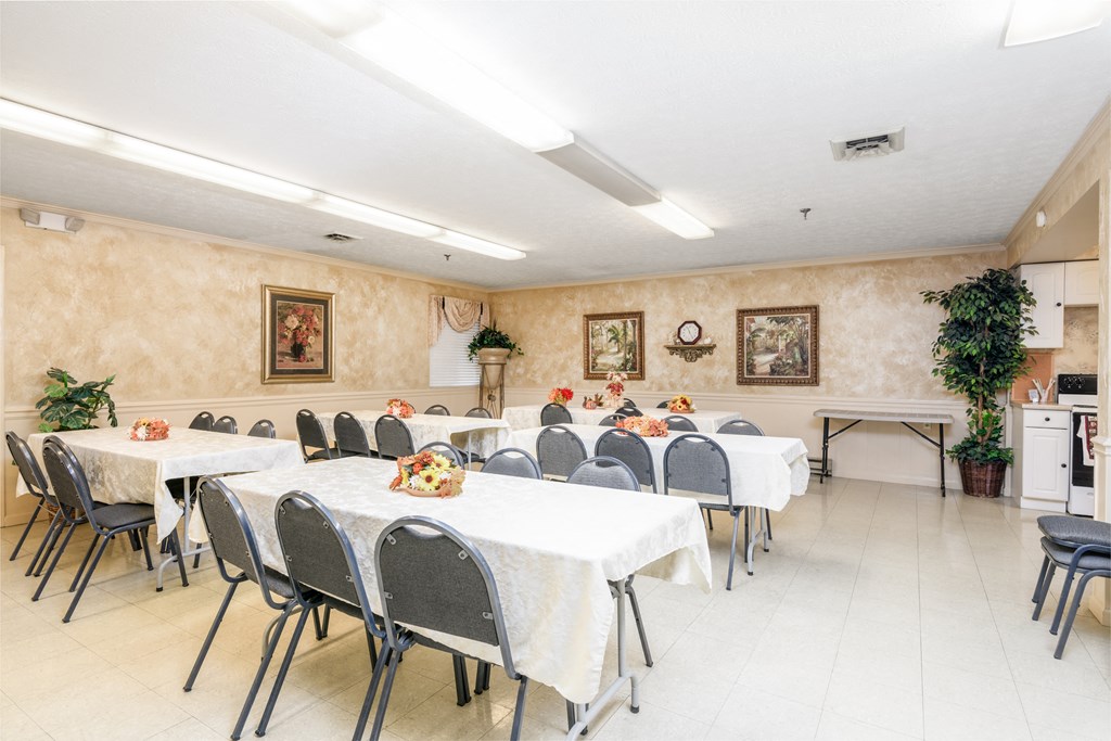 a dining room with long tables and chairs and a kitchen