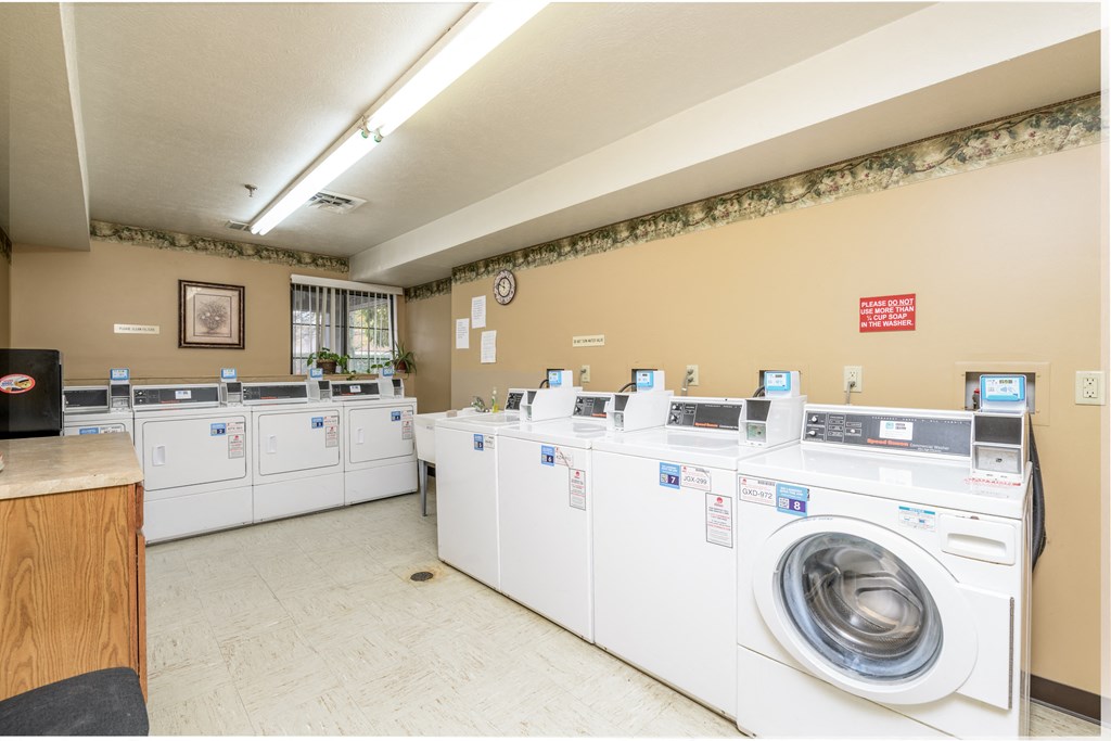 a washer and dryer room with a row of washing machines in a laund