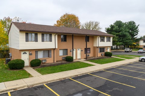 a tan and white apartment building with a parking lot