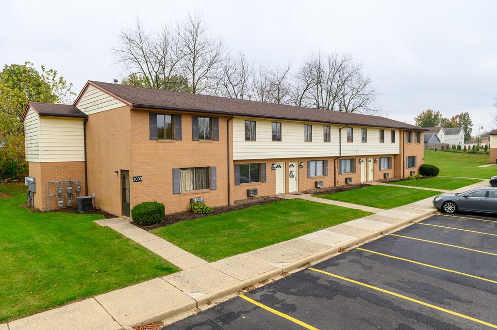 the front of a brick apartment building with green grass
