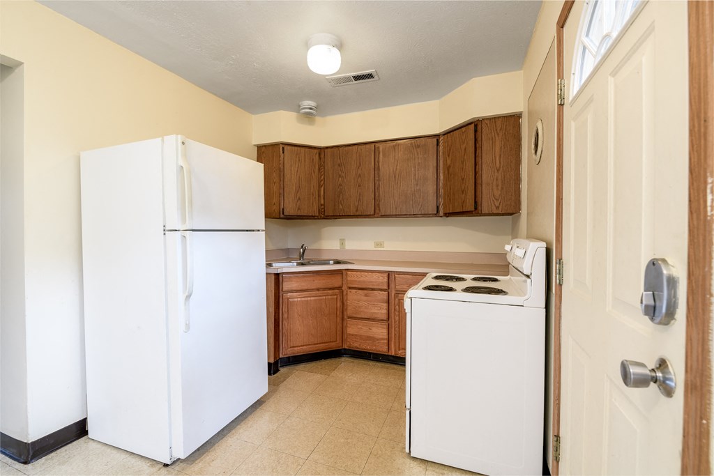 a kitchen with white appliances and wooden cabinets and a white refrigerator