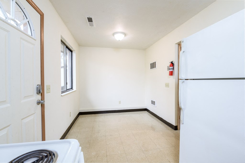an empty kitchen with white appliances and a refrigerator