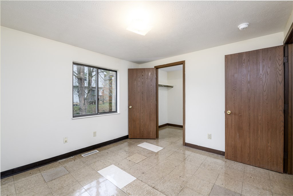 an empty room with white walls and a wooden door and a window