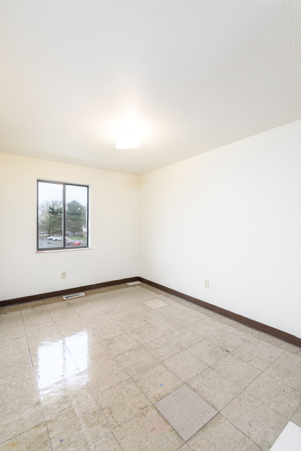 an empty living room with white walls and a window