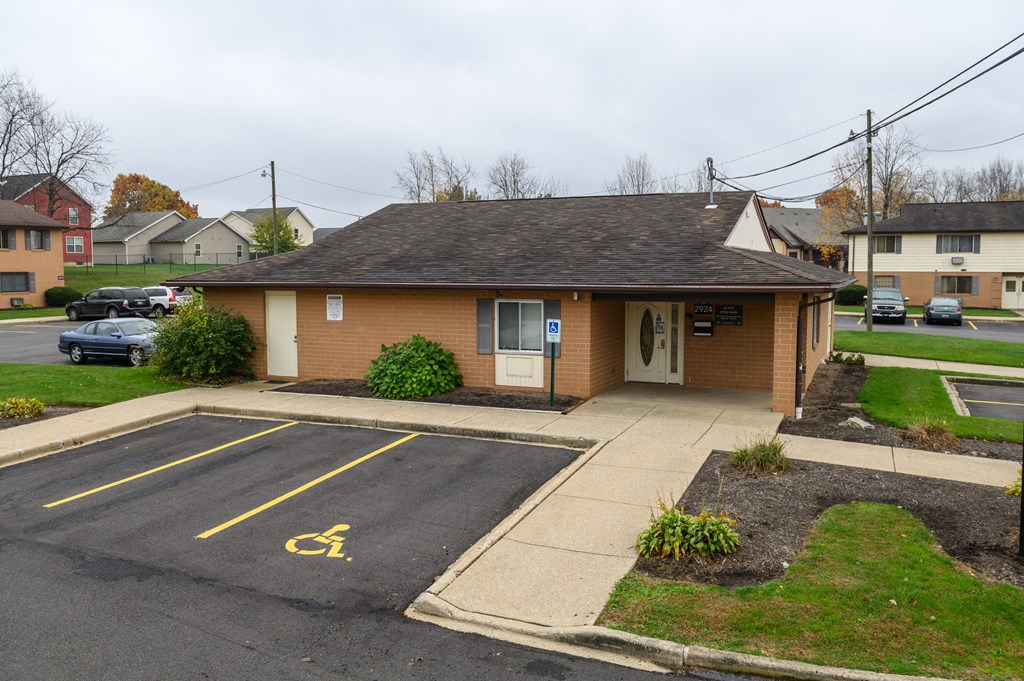a small brown building with a driveway and a parking lot