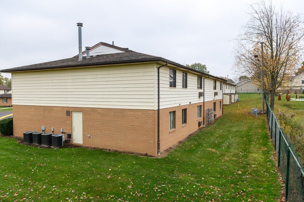 the side of a house with a yard and a fence