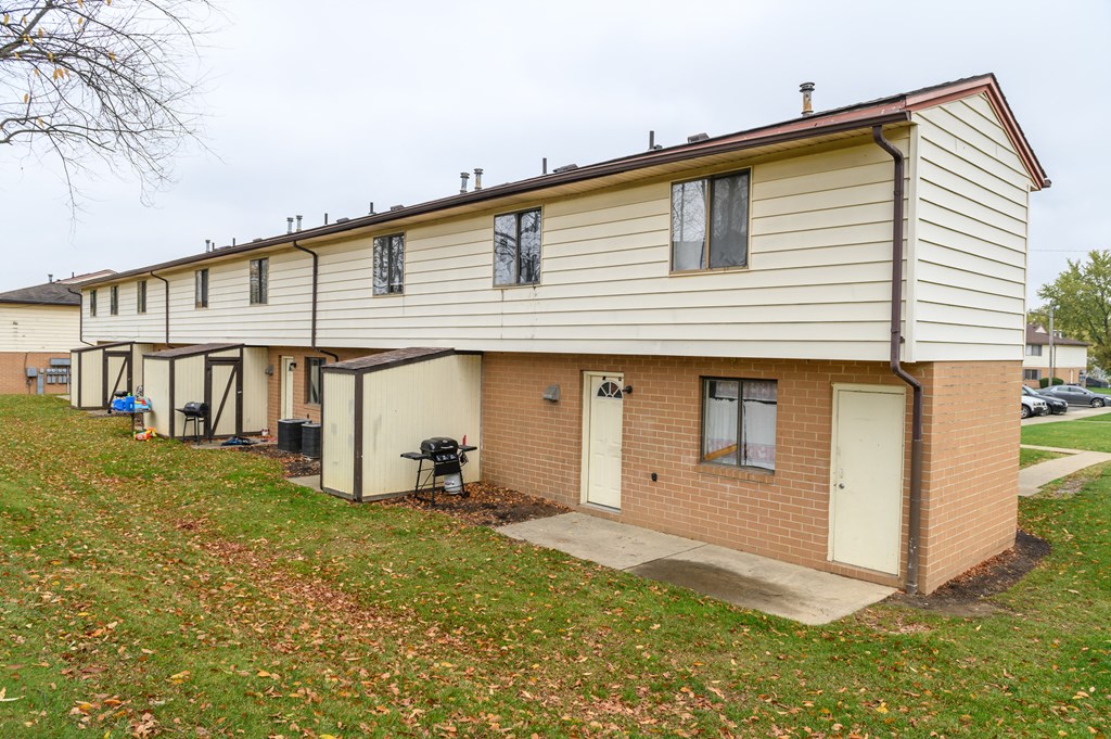 a row of white and brick apartments on the side of a lawn
