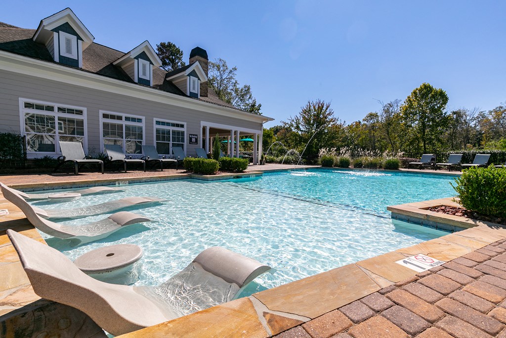 a large pool with chairs and a house in the background