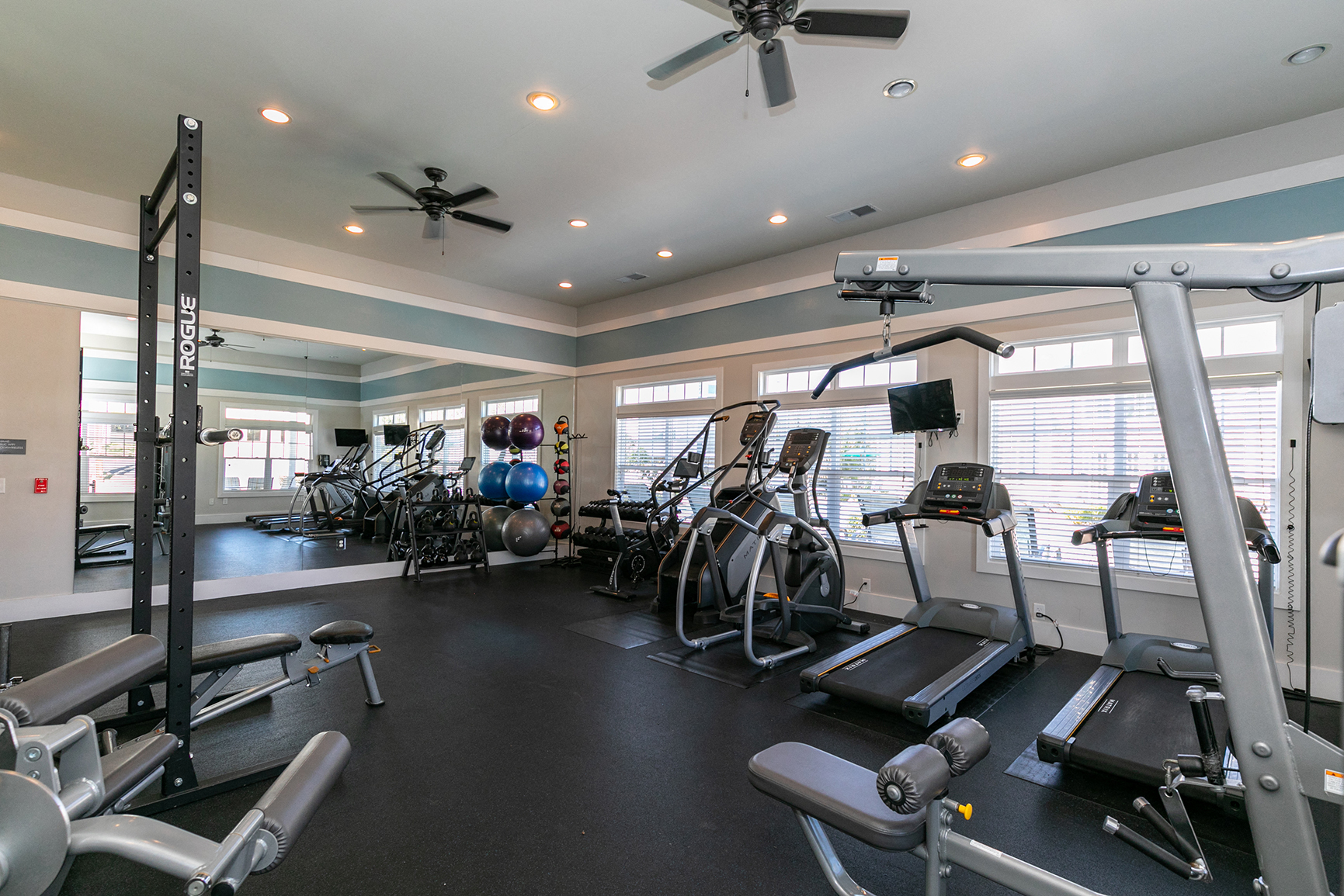 spacious gym with cardio equipment and windows at the district at highland village apartments