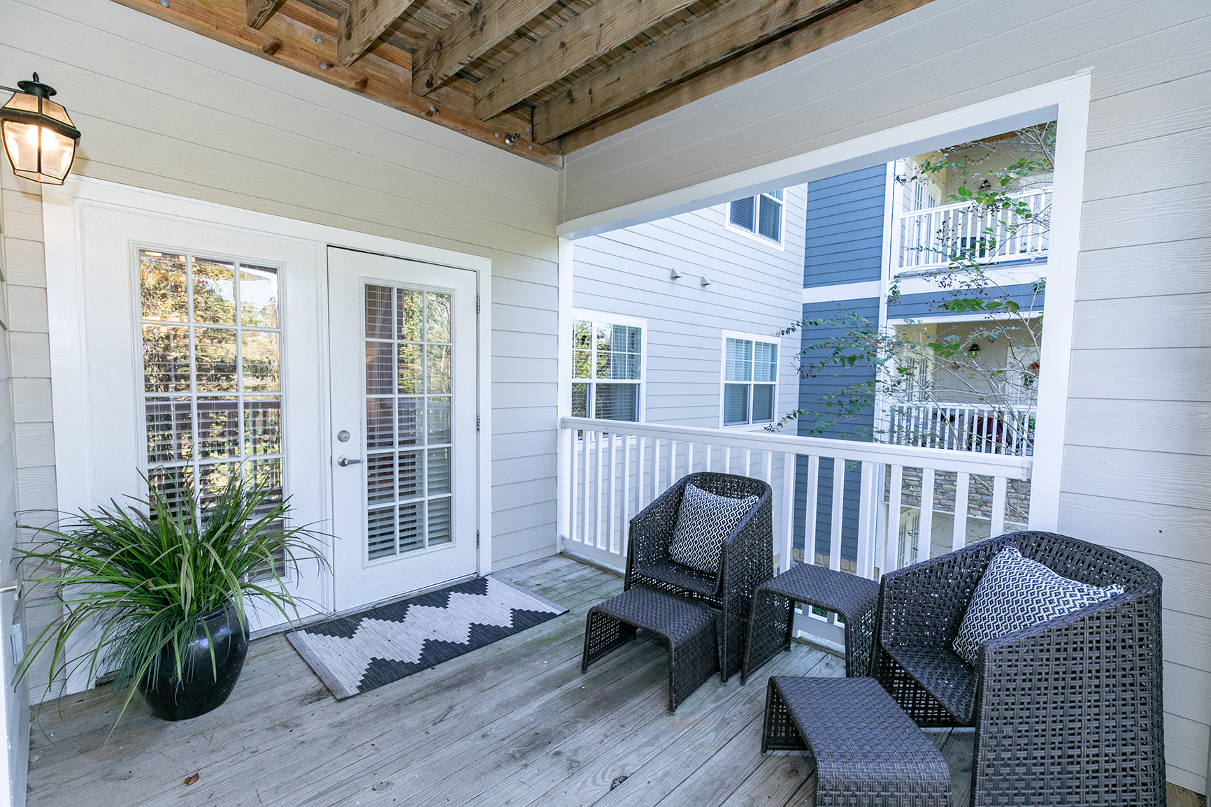 a covered porch with two chairs and a potted plant