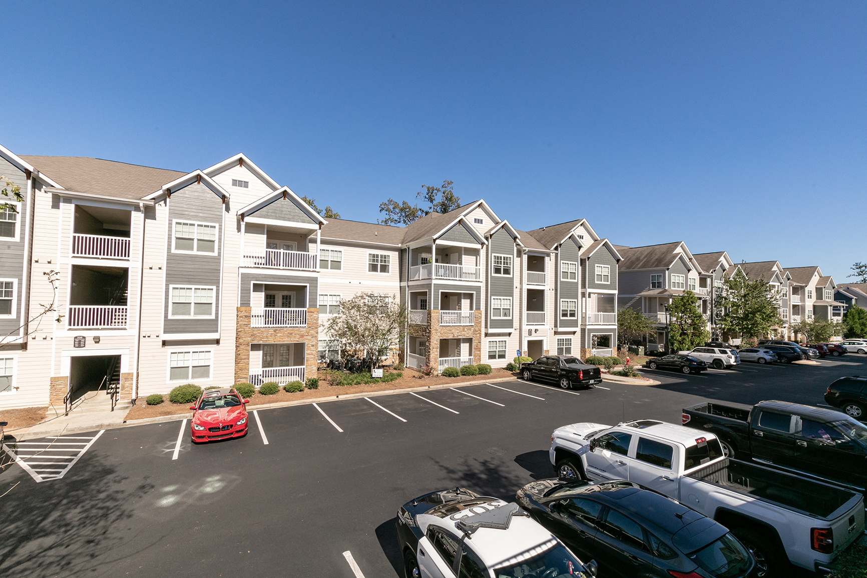 a parking lot with cars in front of an apartment building