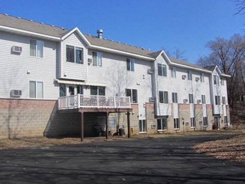 a white building with a balcony and a parking lot