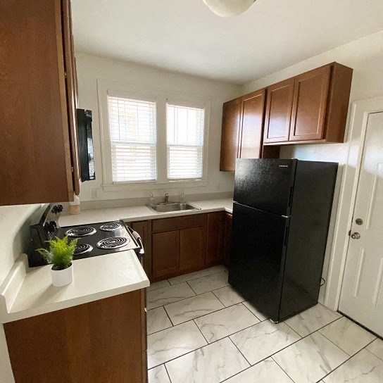 a kitchen with a black refrigerator and a sink