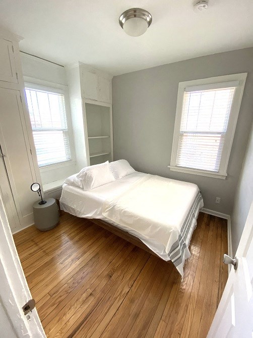a small bedroom with a bed and a wood floor
