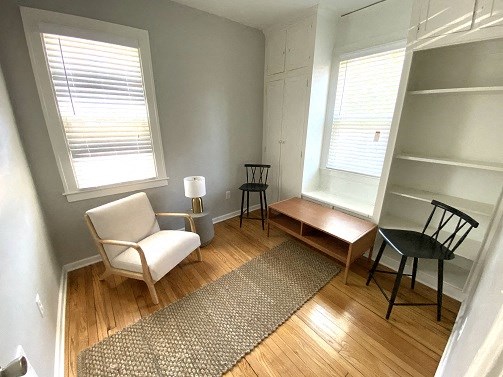 a living room with a chair and a table and two windows