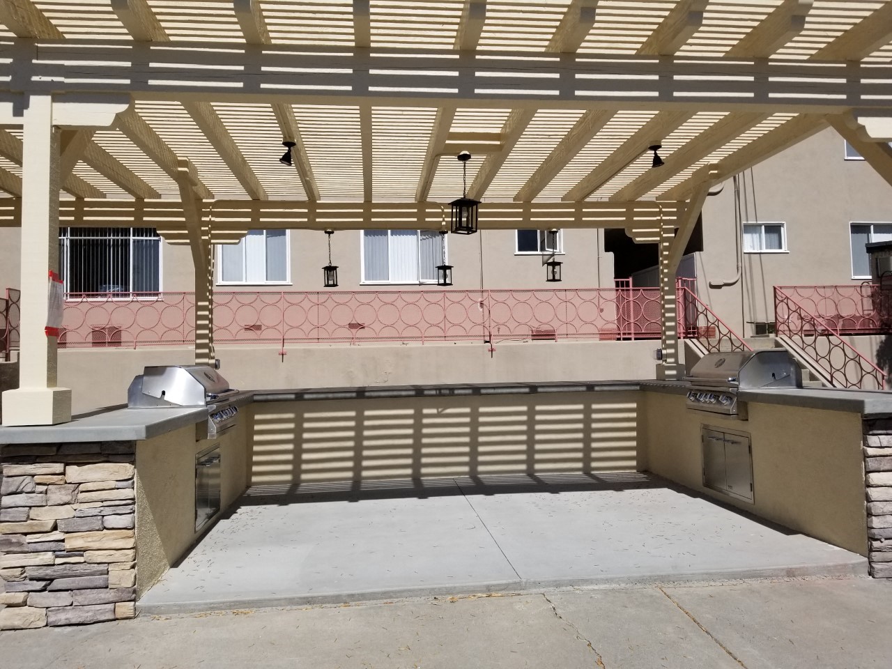 a patio with a grill and a building in the background