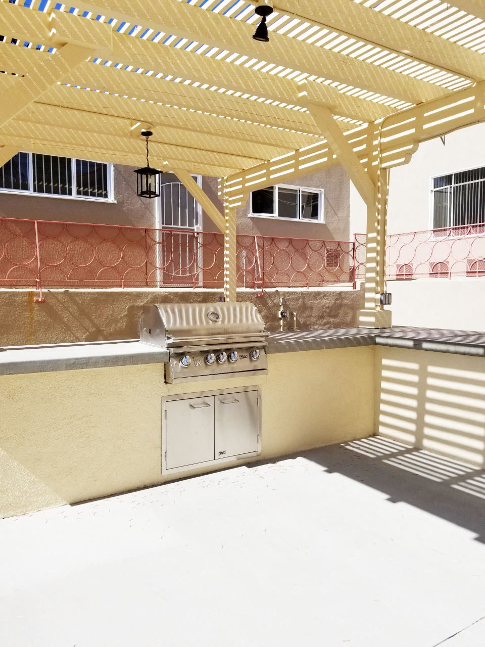 a backyard kitchen with a grill and a pergola