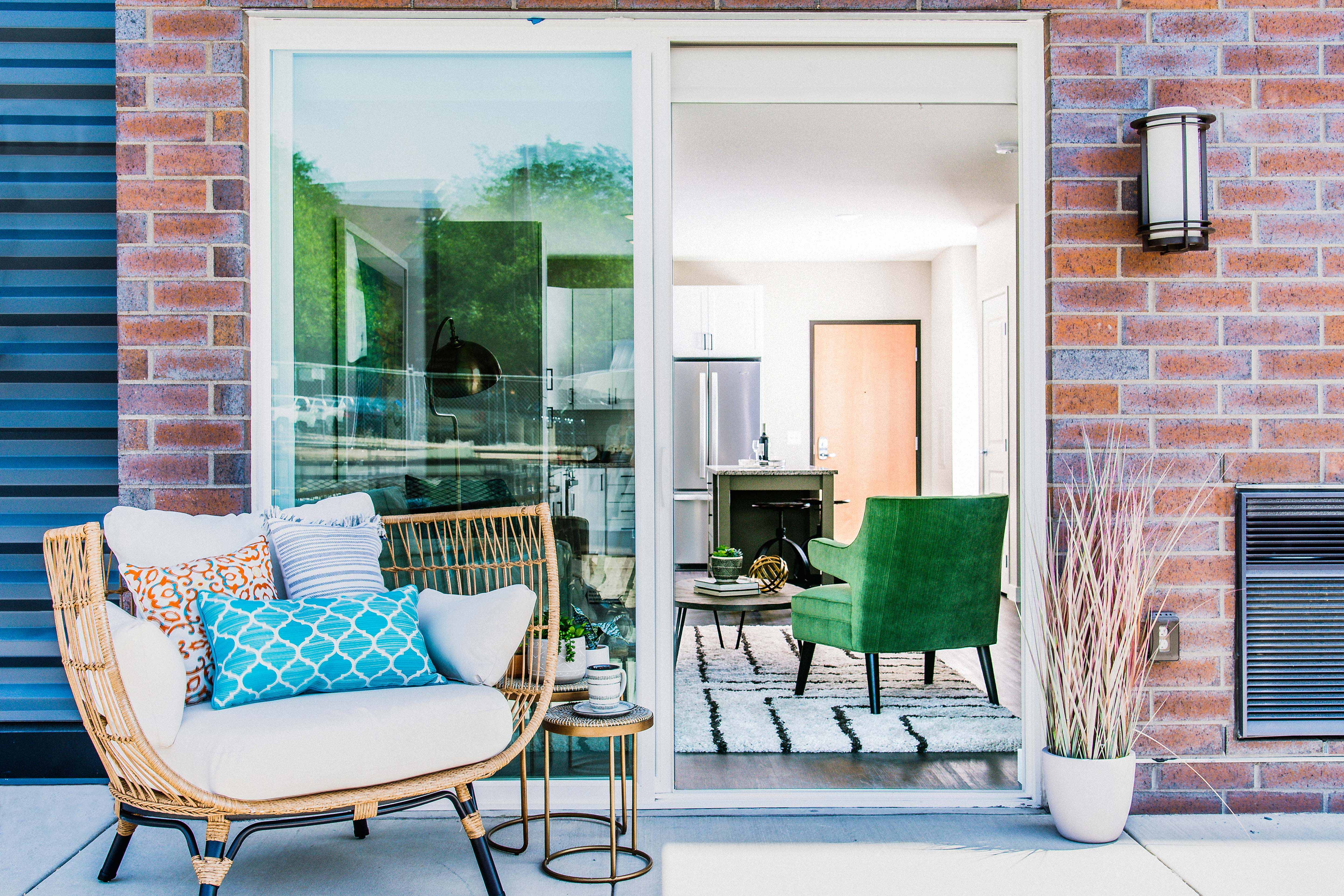 Cozy one-bedroom apartment patio accessible from the kitchen area through a sliding door. The outdoor space features a small seating area for relaxation or outdoor dining.