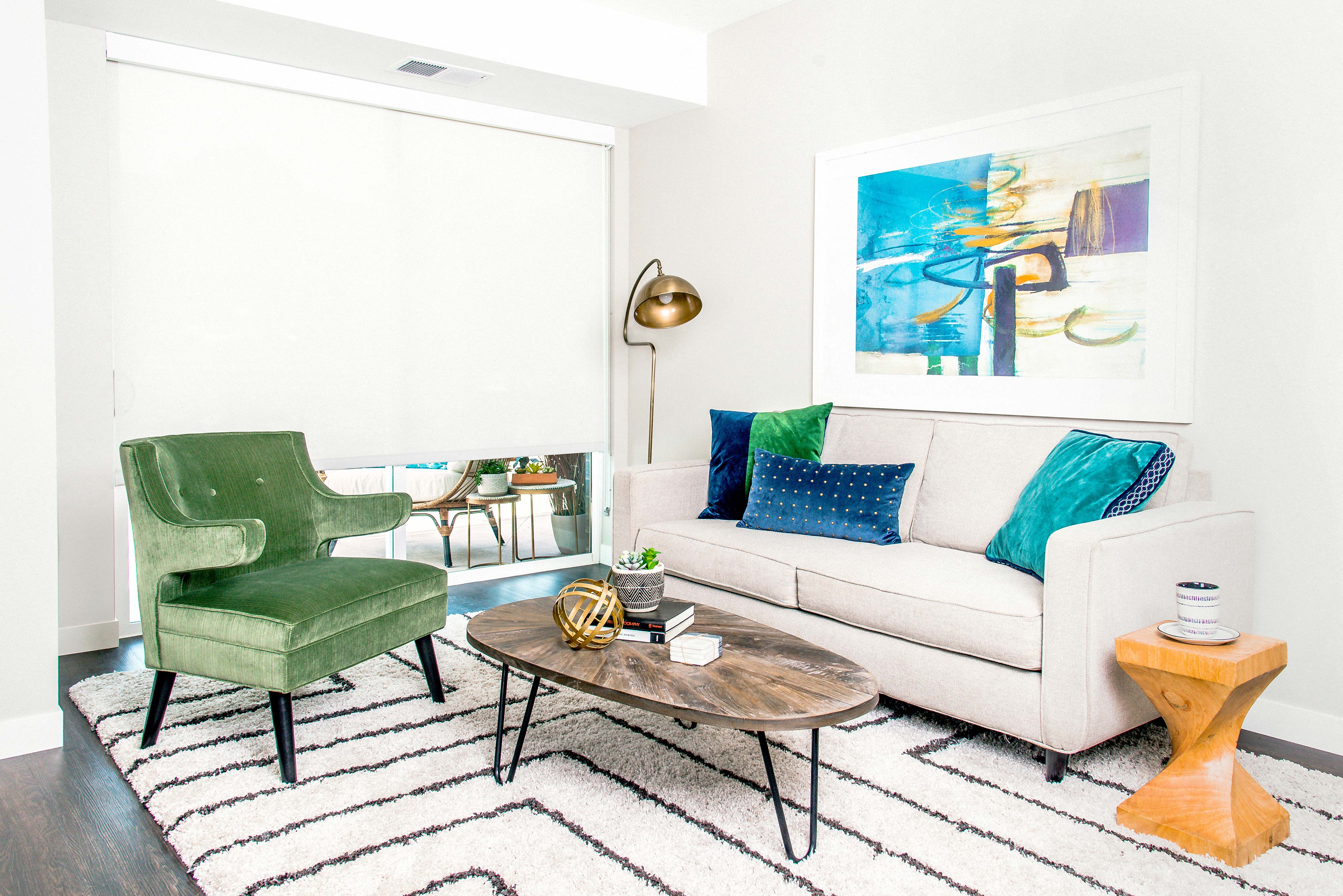 Living room with stain-resistant flooring, showcasing a sliding door leading to a charming patio. Floor-to-ceiling blinds adorn the windows, offering both style and functionality.