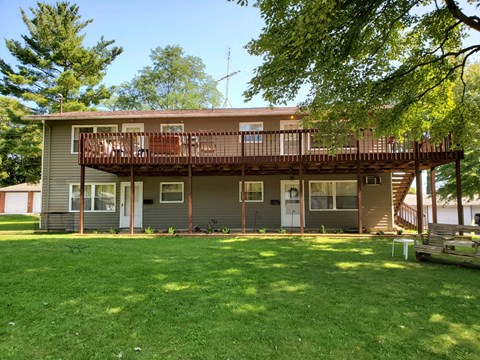 A house with a balcony and a green lawn.