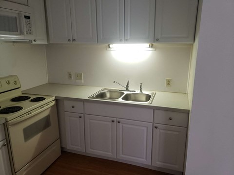 A kitchen with white cabinets and a stove top oven.