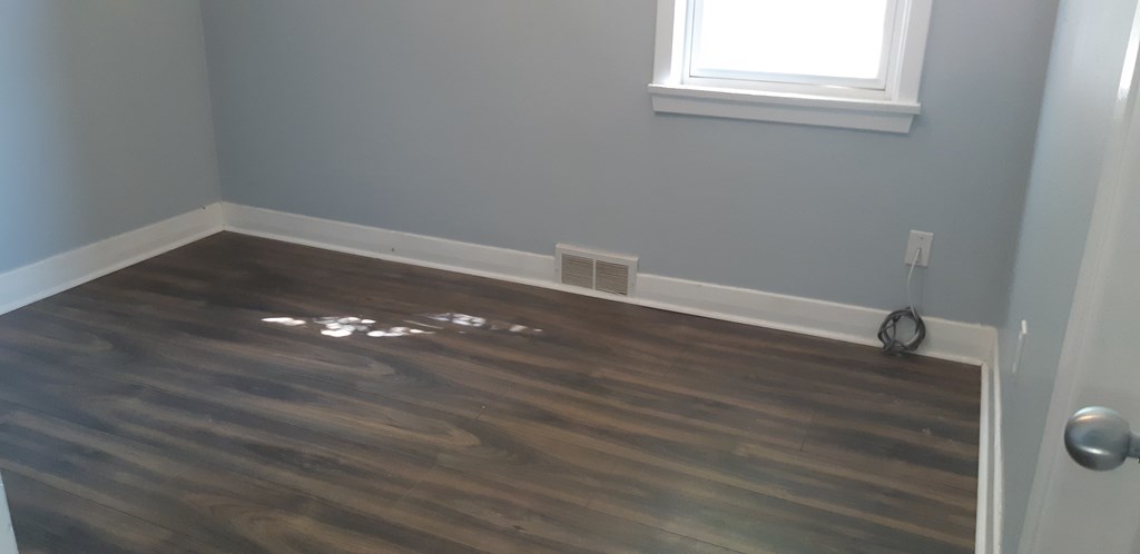 a room with wood flooring and a window and a wall with grey walls