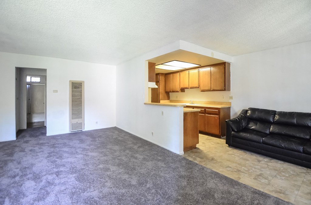 an empty living room with a couch and a kitchen