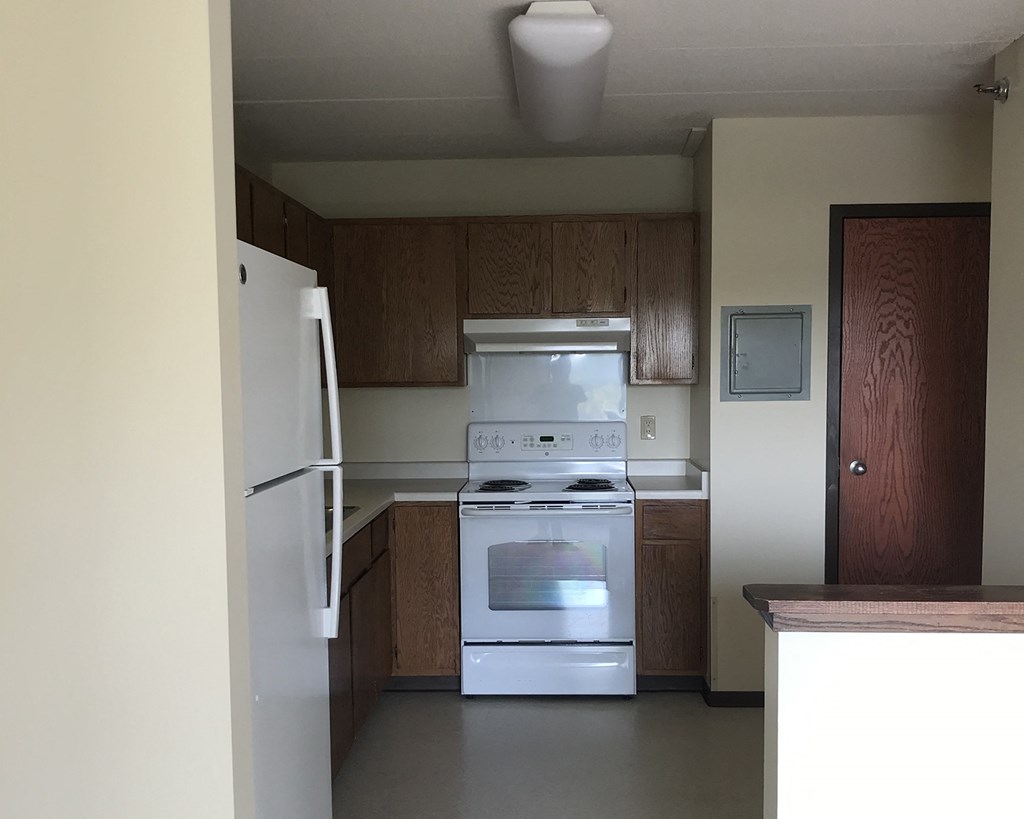 an empty kitchen with white appliances and wooden cabinets