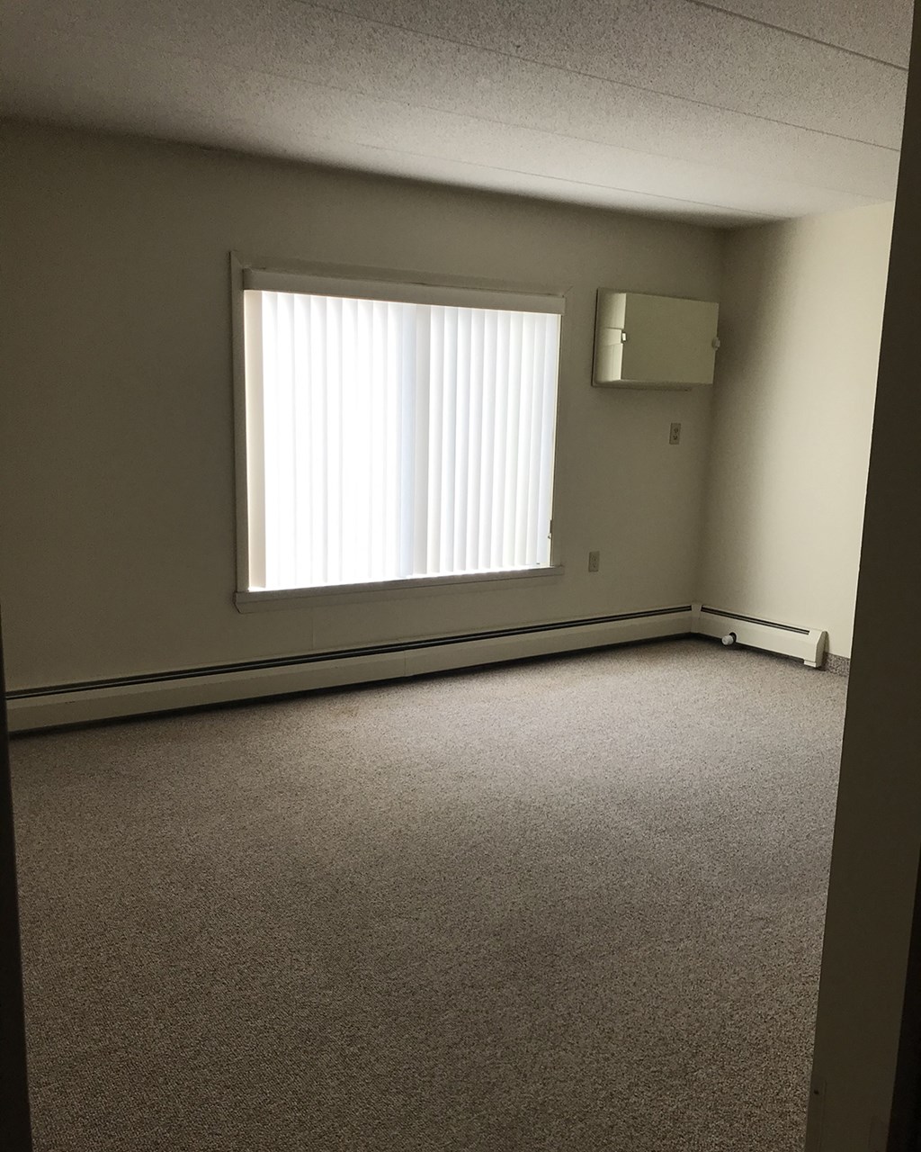 an empty room with a window and a radiator