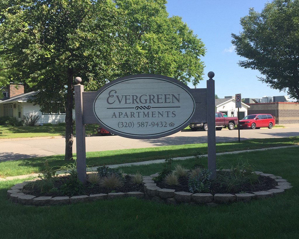 a sign for evergreen apartments on the side of the road